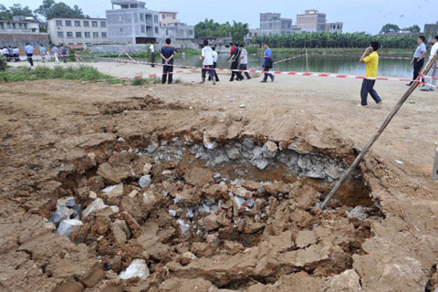 In this photo released by China's Xinhua News Agency, villagers walk past a sinkhole in Tanluo Village of Nanning City, south China's Guangxi Zhuang Autonomous Region, Saturday, June 2, 2012. More than 800 villagers have been evacuated after land sank in the province Friday, which is known for its karst topography. (AP Photo/Xinhua, Zhou Hua)