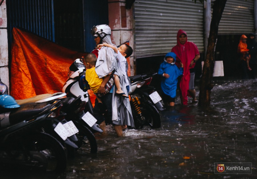 Phụ huynh ẵm bồng con nhỏ, bì bõm lội nước về nhà sau con mưa lớn ở Sài Gòn - Ảnh 10.