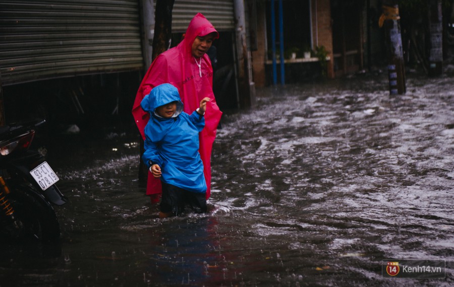 Phụ huynh ẵm bồng con nhỏ, bì bõm lội nước về nhà sau con mưa lớn ở Sài Gòn - Ảnh 9.