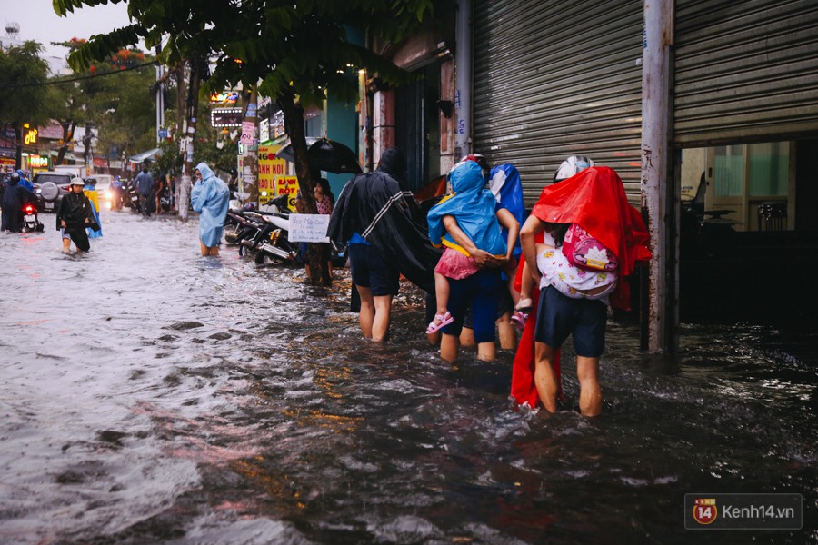 Phụ huynh ẵm bồng con nhỏ, bì bõm lội nước về nhà sau con mưa lớn ở Sài Gòn - Ảnh 12.
