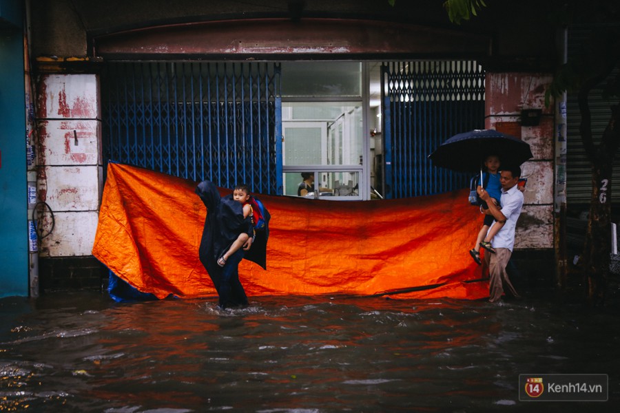 Phụ huynh ẵm bồng con nhỏ, bì bõm lội nước về nhà sau con mưa lớn ở Sài Gòn - Ảnh 5.
