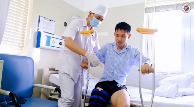 Hùng Dũng được bác sĩ hỗ trợ để có những bước đi đầu tiên sau khi phẫu thuật. Ảnh: HNFC Hùng Dũng được bác sĩ hỗ trợ để có những bước đi đầu tiên sau khi phẫu thuật. Ảnh: HNFC